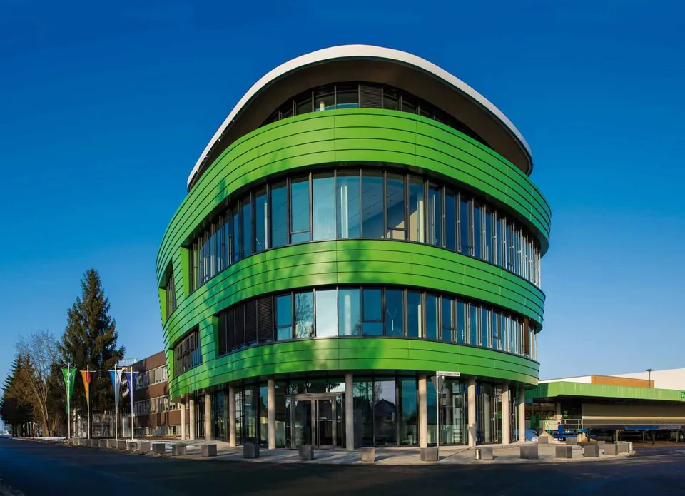 Het moderne, groene ronde kantoorgebouw van Grünbeck onder een blauwe hemel